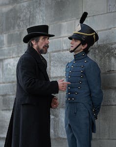 كريستيان بايل بدور أوغسطس لاندور هاري ميلينغ كما يلتقي الكاديت إدغار ألين بو في الشارع.  يرتدي بيل معطفًا أسود طويلًا وقبعة علوية ، بينما يرتدي ميلينغ الزي العسكري الأزرق.