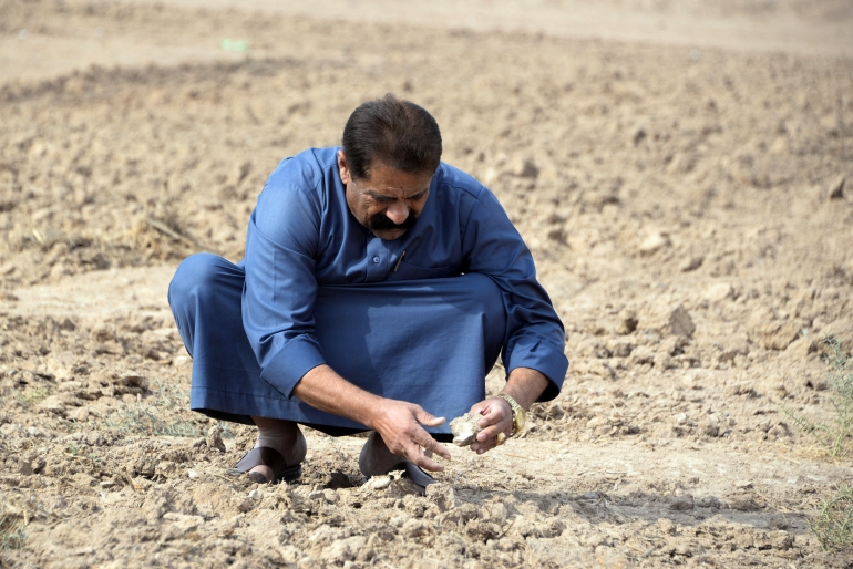 فلّاحون في شمال العراق يهجرون أرضهم بسبب الجفاف - الفرنسية A farmer checks soil compacted by drought on a parcel of agricultural land, on the outskirts of the town of Tel Keppe (Tel Kaif) north of the city of Mosul in the northern Iraqi province of Nineveh, on October 26, 2021. - For centuries, the province's "Fertile Crescent" was the bread basket of Iraq with its 6,000 square kilometres of arable land, said a spokesman for the agriculture ministry, but experts have warned that the dry spell and record low precipitation, compounded by climate change, are threatening social and economic disaster in the war-scarred country. (Photo by Zaid AL-OBEIDI / AFP)