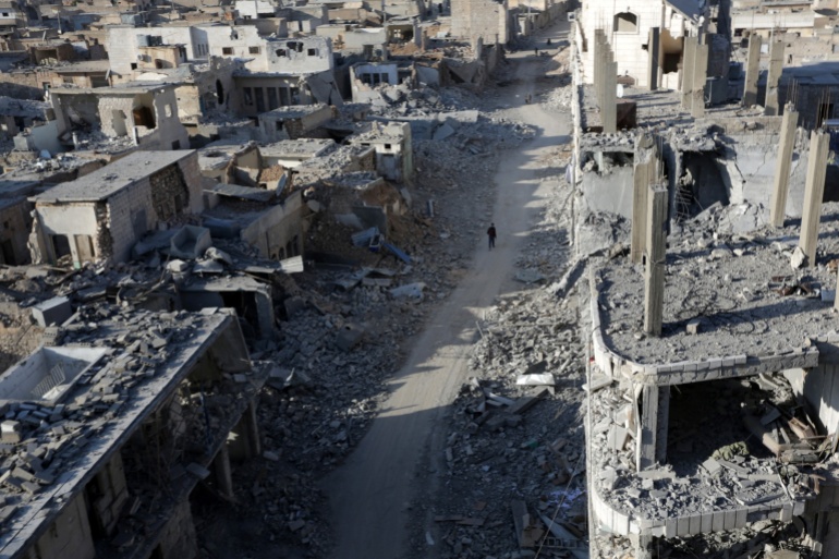 People walk along a damaged neighbourhood in the northern Syrian town of al-Bab