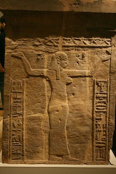 نقش على الحجر يصور امرأة تقف وذراعها مرفوعان.